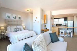 a bedroom with a bed and a couch and a kitchen at Morakani Studio 503 in Green Point. in Cape Town