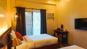 a hotel room with two beds and a window at UNWND Boutique Hotel Camiguin in Mambajao