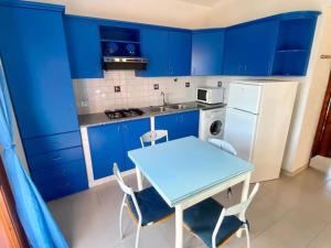 a blue kitchen with a table and blue cabinets at Appartamento Lucca 2 in San Teodoro