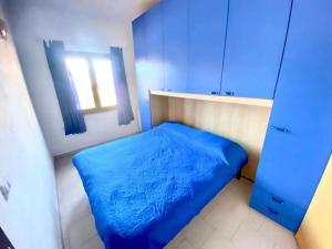 a small bedroom with a blue bed and a window at Appartamento Lucca 2 in San Teodoro