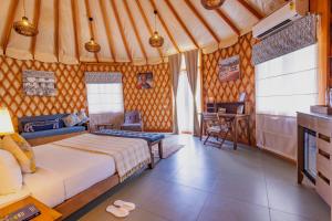a bedroom with a bed and a desk in a room at Machaan Wilderness Lodge Nagarahole in Srimangala