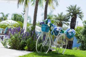 - un vélo blanc avec des fleurs bleues dans des paniers dans l'établissement B&B Villa Eraclea, à Villaggio Mosè