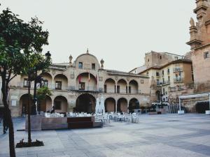 un bâtiment avec des tables et des chaises dans une cour dans l'établissement La Colegiata Suite, à Lorca