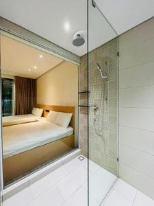 La salle de bains est pourvue d'une douche, d'un lit et d'une cabine de douche en verre. dans l'établissement Căn hộ nghỉ dưỡng 5 sao APEC MANDALA PHÚ YÊN, à Liên Trì (3)