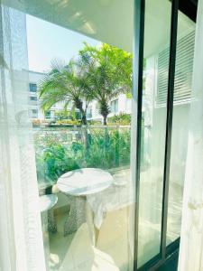 d'un balcon en verre avec une table et des palmiers. dans l'établissement Căn hộ nghỉ dưỡng 5 sao APEC MANDALA PHÚ YÊN, à Liên Trì (3)