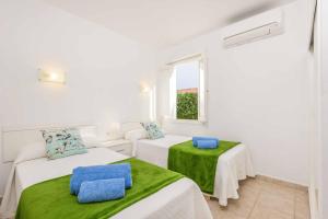 two beds in a white room with a window at Villa Tia Dora in Cala en Blanes +19 photos