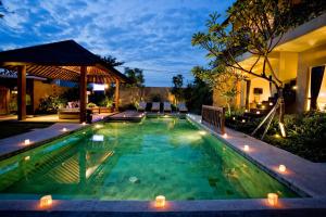 a swimming pool with lights in a backyard at night at Villa Cokelat in Canggu