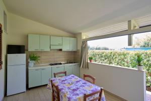 eine Küche mit weißen Schränken, einem Tisch und einem Fenster in der Unterkunft Villaggio Santa Maria in Capo Vaticano