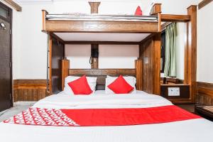 1 dormitorio con 1 cama grande con almohadas rojas en Hotel Cottage Crown Plaza By My Rooms en Nueva Delhi