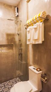 a bathroom with a shower and a toilet and towels at UNWND Boutique Hotel Camiguin in Mambajao +54 photos