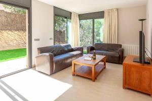 un soggiorno con 2 divani in pelle e una TV di Villa Vista Alegre a Palafrugell