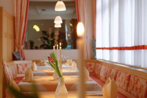 einen Tisch mit weißen Vasen und Blumen in einem Restaurant in der Unterkunft Hotel Restaurant Talblick in Bad Ditzenbach
