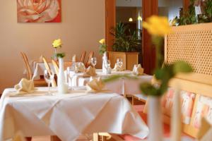 a group of tables with white tablecloths and flowers at Hotel Restaurant Talblick in Bad Ditzenbach