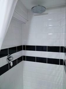 a bathroom with a shower with black and white tile at The Cosy Pad Glan Y Morfa Bach in Tywyn