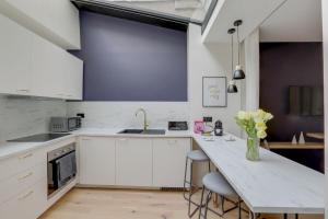 a kitchen with white cabinets and a counter with a vase of flowers at 140 Suite Ludo - Superbe Appartement à Paris in Paris