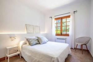 een witte slaapkamer met een bed en een raam bij Villa Garrigo in Pollença