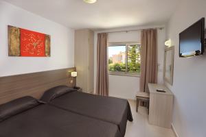 a bedroom with a bed and a tv and a window at Petrosana Hotel Apartments in Ayia Napa