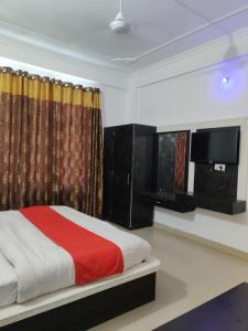 1 dormitorio con 1 cama y TV. en Hotel Parbhat Palace, en Katra