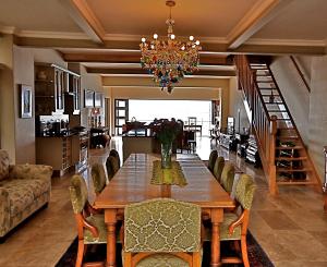 a dining room table with chairs and a chandelier at Driftwood Beach Villa in Gordonʼs Bay