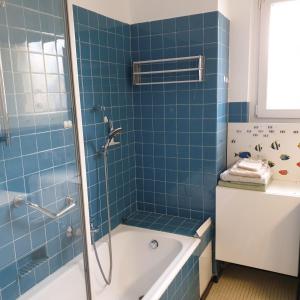 La salle de bains est pourvue de carrelage bleu, d'une baignoire et d'une douche. dans l'établissement Côté parc, à Schiltigheim