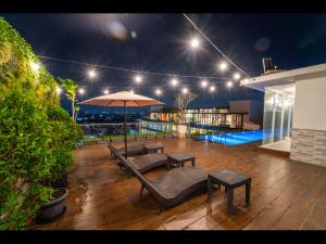 a patio with chairs and an umbrella at night at Grand Altuz Hotel Yogyakarta in Seturan