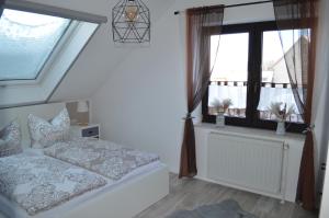 um quarto com uma cama e duas janelas em Apartment unterhalb der Burg Hanstein em Bornhagen