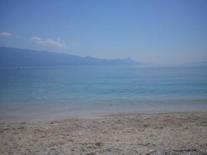 a beach with the ocean and mountains in the background at Apartment Tara in Sumartin