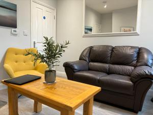 a living room with a leather couch and a table at Eclipse House in Newmarket