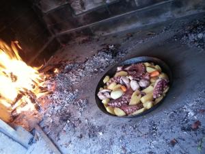 a pan filled with food next to a fire at Apartment Tara in Sumartin