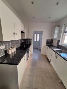 a large kitchen with white cabinets and black counter tops at Anfield Abbey House in Liverpool