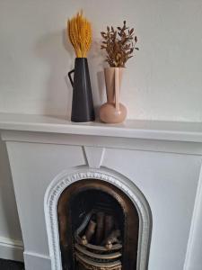 a fireplace with two vases and flowers on a shelf at Anfield Abbey House in Liverpool