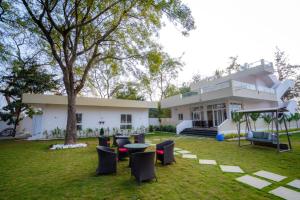 The Neem Tree -4br pool villa في شاميربت: بيت فيه ساحه فيها كراسي وشجر