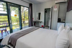 a bedroom with a white bed and a large window at SleepOver Kruger Gate in Skukuza