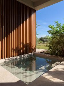 una piscina riflettente di fronte a un edificio con recinzione di Ilya Botanic Suites a Steni Vala Alonissos