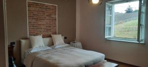 ein Schlafzimmer mit einem Bett mit Ziegelwand in der Unterkunft Cà Trifolera Barbaresco - Cascina vista vigneti con Cantina per degustazioni - Wi-Fi Parcheggio gratuito in Barbaresco