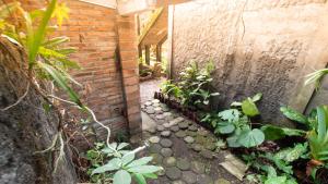 um pequeno jardim com plantas e uma parede de tijolos em Rumah Gaharu - Kamar Ngarep 002 em Sleman
