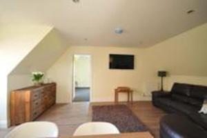 a living room with a black couch and white chairs at Home from home in Lee-on-the-Solent