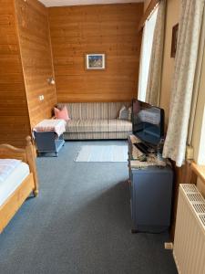 Una sala de estar con un sofá y un televisor. en Pension Huber, en Fischbachau