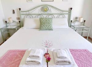a bedroom with a white bed with two towels at Camera Ponente in Tanaunella