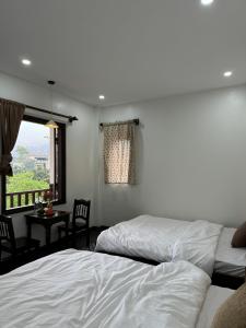 1 dormitorio con 2 camas, mesa y ventana en Anio Ha Giang Hotel, en Ha Giang