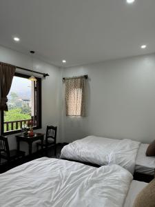 a bedroom with two beds and a table and a window at Anio Ha Giang Hotel in Ha Giang