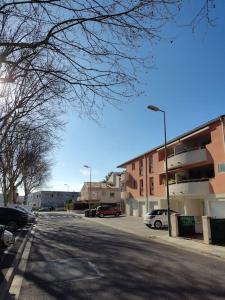 an empty street with cars parked in a parking lot at Joli appartement dans quartier calme de Perpignan in Perpignan