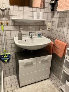 ein Badezimmer mit einem Waschbecken und einer weiß gefliesten Wand in der Unterkunft Ferienwohnung Angelika in Kressbronn am Bodensee
