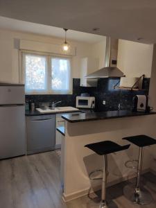 a kitchen with a counter and two bar stools at Joli appartement dans quartier calme de Perpignan in Perpignan