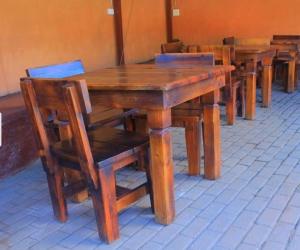 a row of wooden tables and chairs in a room at Butterfly tree guesthouse in Phalaborwa
