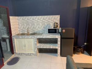La cuisine est équipée d'un comptoir avec évier et d'un réfrigérateur. dans l'établissement Fullmoon Jomtien Guest house, à Jomtien Beach