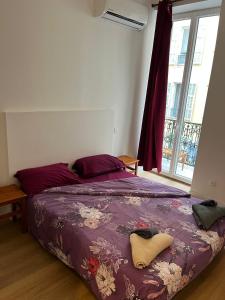 een slaapkamer met een bed met een paars dekbed en een raam bij Hôtel Lyonnais in Nice