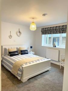 a bedroom with a large white bed and a window at Contemporary Holiday apartment in Perranporth