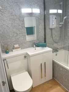y baño con aseo, lavabo y espejo. en Contemporary Holiday apartment, en Perranporth