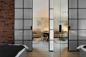 a bedroom with glass doors leading into a living room at Elite Apartments Sienna Grobla Prestige in Gdańsk